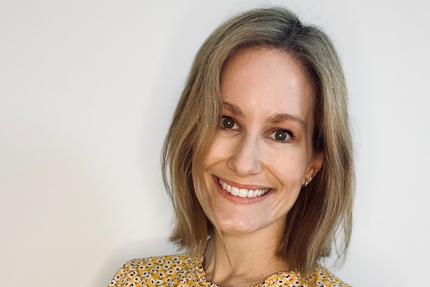 A headshot of a smiling woman with short blonde hair. 
